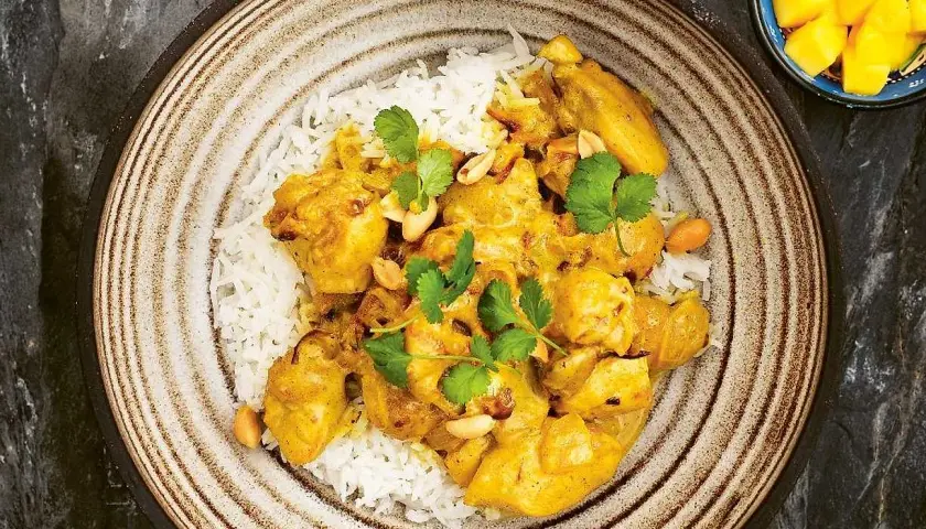 En krämig kycklingcurry med ris, toppad med koriander och jordnötter. En riktig curry nam nam!