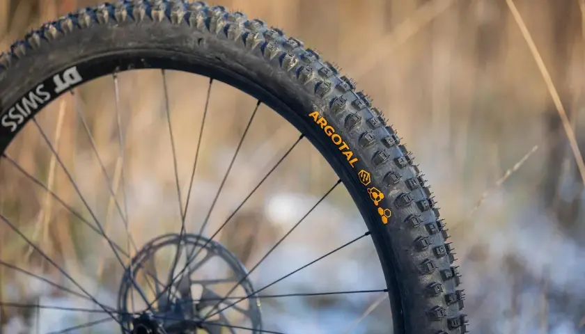 Close-up of a DT Swiss wheel with Argotal tires, showcasing their aggressive tread pattern, perfect for the lightest MTB tires.
