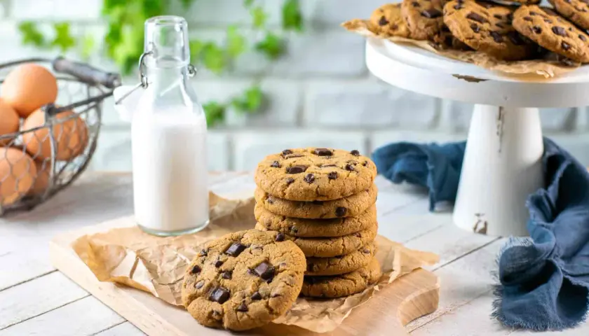 Una pila di biscotti con gocce di cioccolato, pronti per essere gustati con un bicchiere di latte.