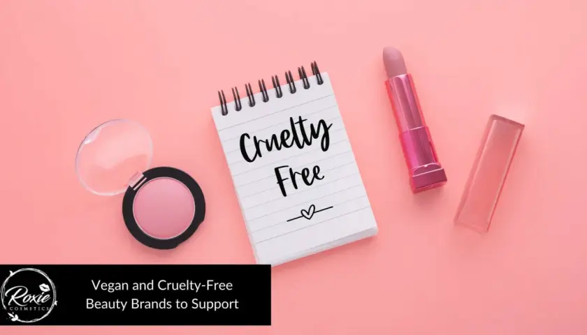 Różowy róż, błyszczyk i szminka na pastelowym tle. Notatnik z napisem "Cruelty Free" podkreśla, że to kosmetyki nietestowane na zwierzętach.