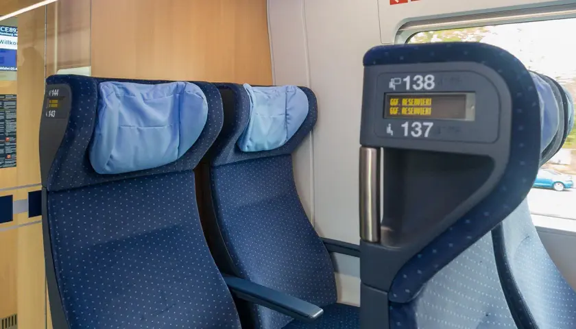 Blaue Sitze im Zug, mit Kopfkissen. Auf dem Display steht "Reserviert". Eine Reise durch Europa, vielleicht mit dem ICE.