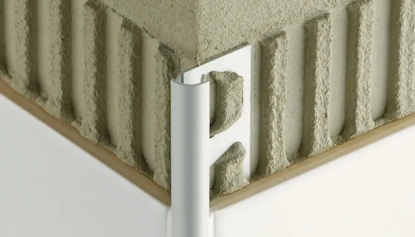 Angolo di un muro con adesivo per piastrelle e un elegante bordino piastrelle in alluminio.