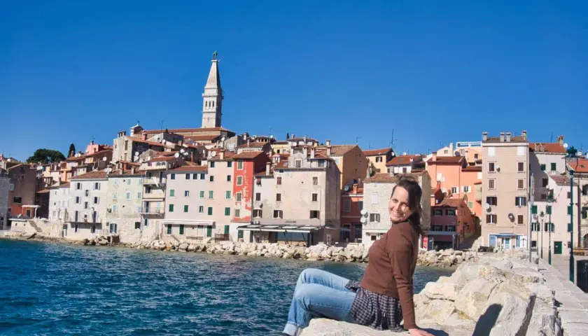 Frau sitzt auf Felsen mit Blick auf die Küstenstadt Rovinj in Kroatien.