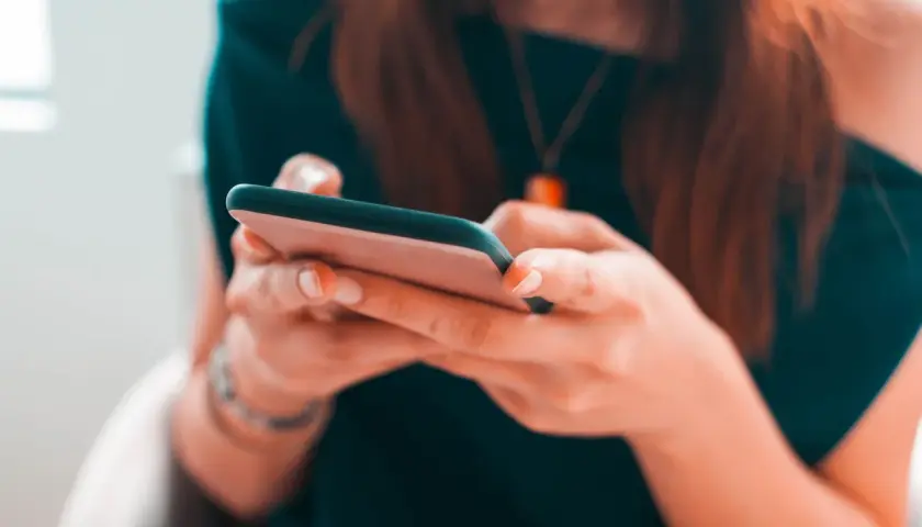 Kobieta pisze na telefonie, zastanawiając się, czy na Vinted można płacić za pobraniem.
