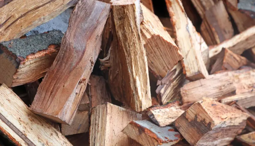 Stapel von gespaltenem Brennholz, bereit für den Kamin. Das Holz zeigt die Maserung und Rinde, die den hohen Brennwert beeinflussen.
