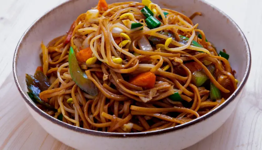 En skål med utsökt chow mein, full av nudlar, grönsaker och böngroddar.