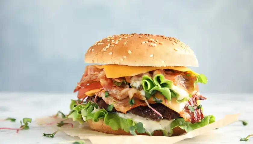 Apetyczny burger z bekonem, serem i warzywami. Czy zastanawiałeś się nad big mac kcal?