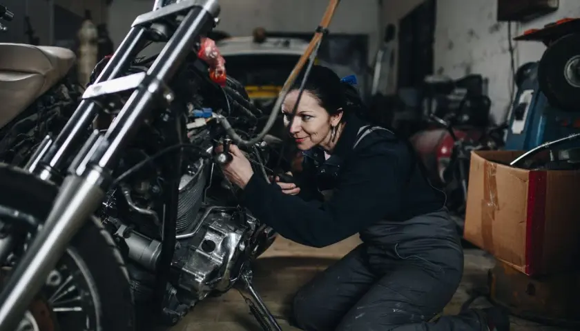 Mecánica arregla una moto ahogada en su taller.