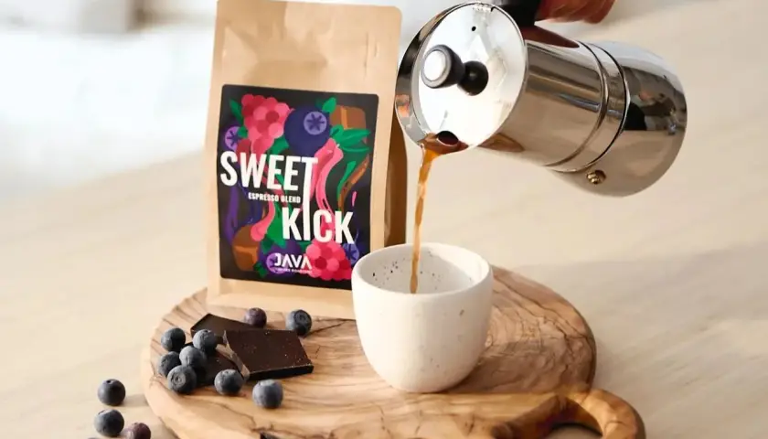 Kawa "Sweet Kick" z kawiarki nalewana do filiżanki. Na desce leżą jagody i czekolada. Idealna ilość kawy do kawiarki.