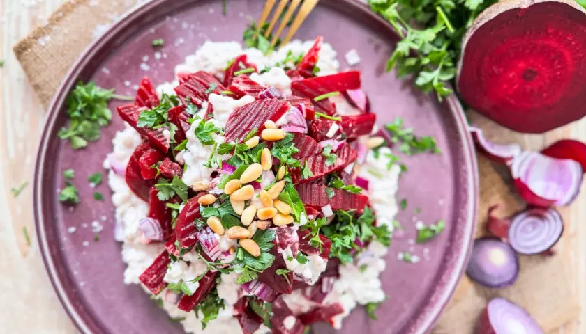 Rote Bete Salat nach Omas Art: ein cremiger Salat mit Rote Bete, Zwiebeln, Pinienkernen und frischer Petersilie, serviert auf einem lila Teller.