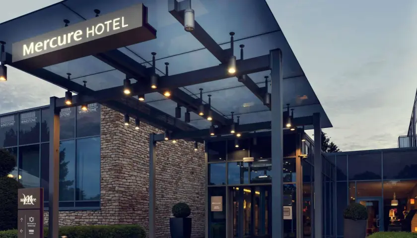 Nowoczesne wejście do hotelu Mercure w Gdańsku, z kamienną fasadą i szklanymi drzwiami.