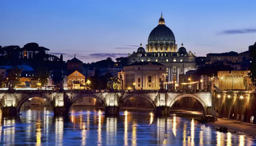 Un suggestivo ponte a Roma illumina il Tevere al crepuscolo, con San Pietro sullo sfondo.