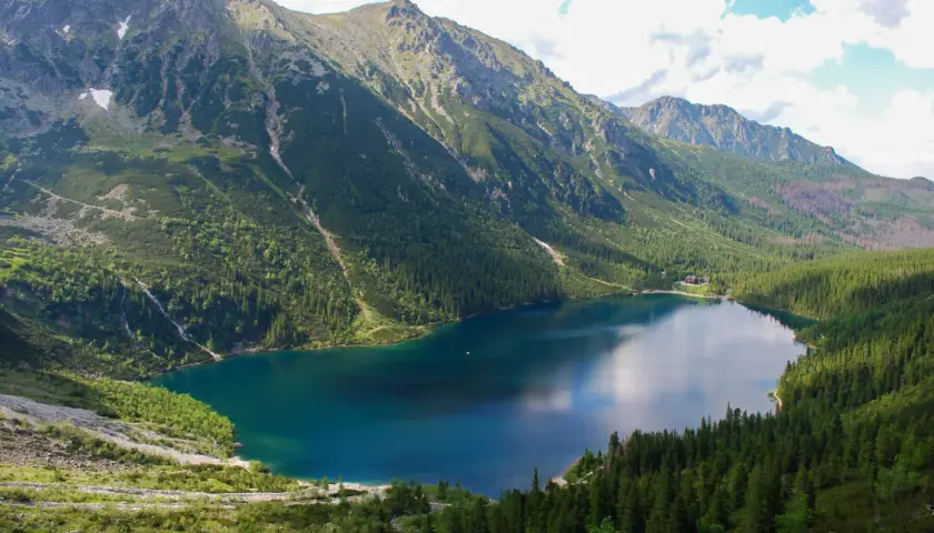 Widok na Morskie Oko, największe jezioro w Tatrach, otoczone stromymi, zalesionymi zboczami gór.