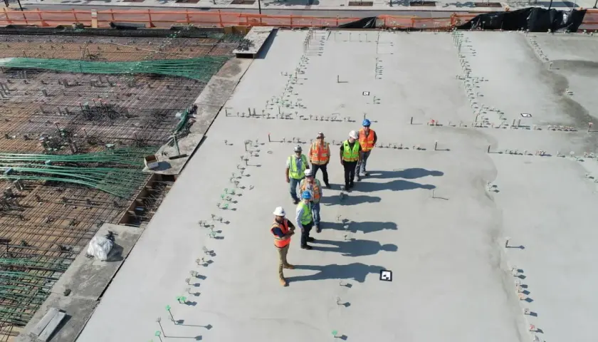 Grupa budowlańców na placu budowy. Zastanawiają się, ile kosztuje kubik betonu, patrząc na zbrojenie i świeżo wylany beton.