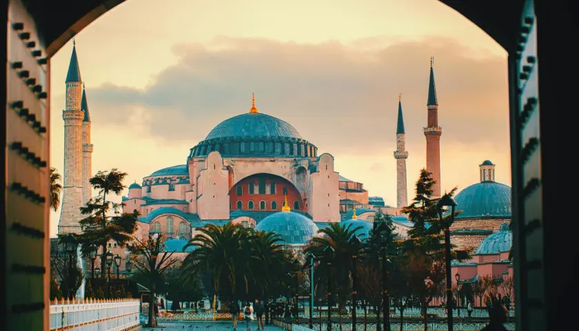 Blick durch einen Torbogen auf die Hagia Sophia mit ihren Kuppeln und Minaretten im Abendlicht. Der Eintritt in dieses historische Meisterwerk ist ein unvergessliches Erlebnis.