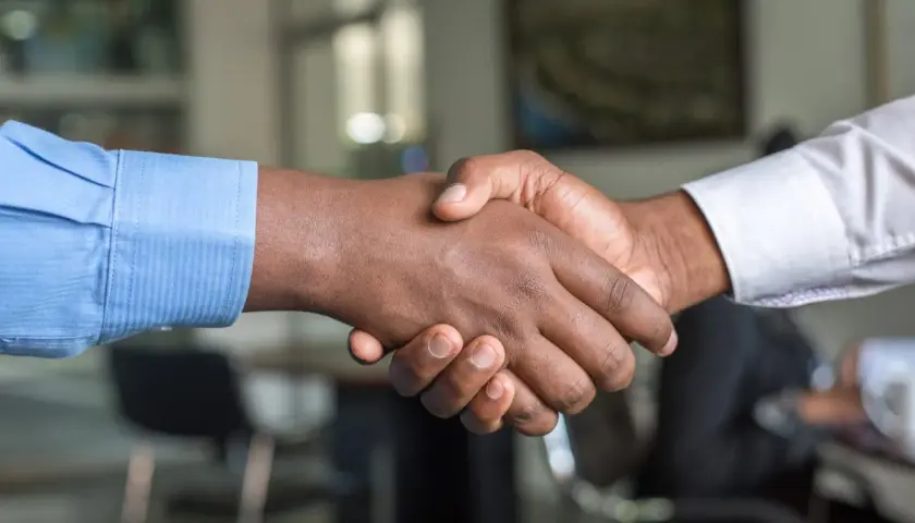 Dos hombres se dan la mano, sellando un acuerdo. Un apretón de manos que podría ser el inicio de un modelo precontrato exitoso.