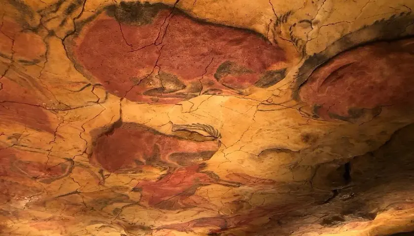 Pinturas rupestres de bisontes en el techo de una cueva, evocando el **museo mitológico Santillana del Mar**.