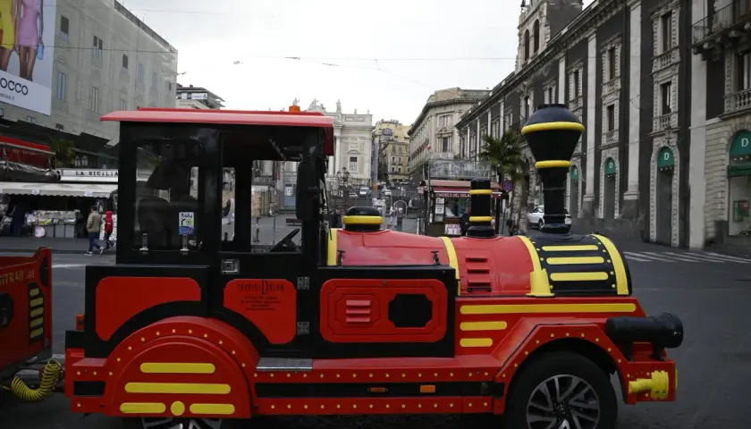 Czerwony pociąg turystyczny "Tourist Dream" na ulicach Katanii, idealny do zwiedzania Syrakuz.