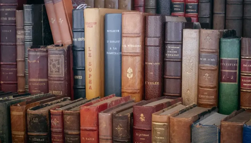 Une pile de livres anciens aux reliures variées. Obtenez une estimation livres anciens gratuit pour vos trésors littéraires.