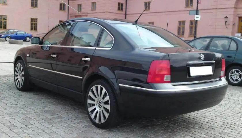 Svart Passat W8 parkerad på kullerstensgata framför en rosa byggnad.