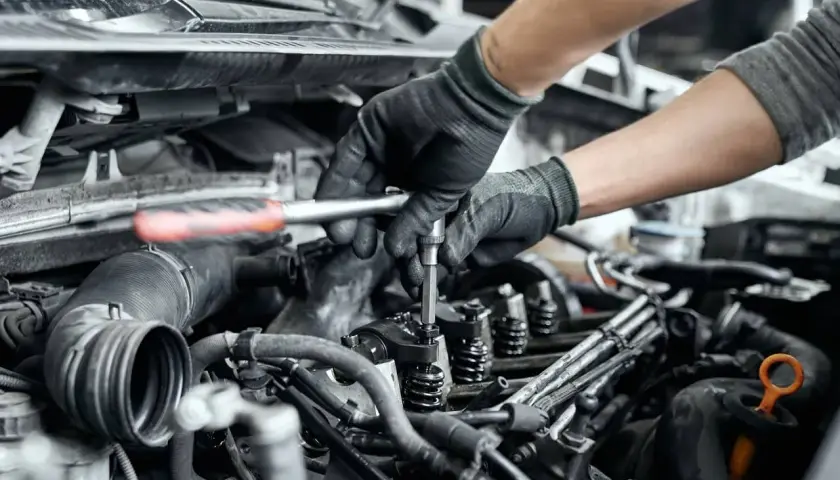 Mechanik naprawia zatarty silnik, używając klucza do dokręcenia części. Olej 0w20 mógł być przyczyną problemu.