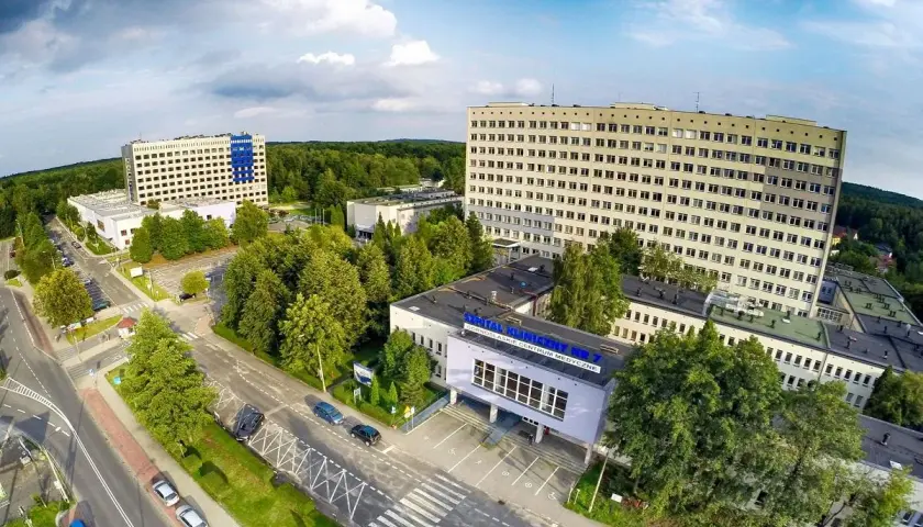 Widok z lotu ptaka na kompleks budynków szpitalnych otoczony zielenią.