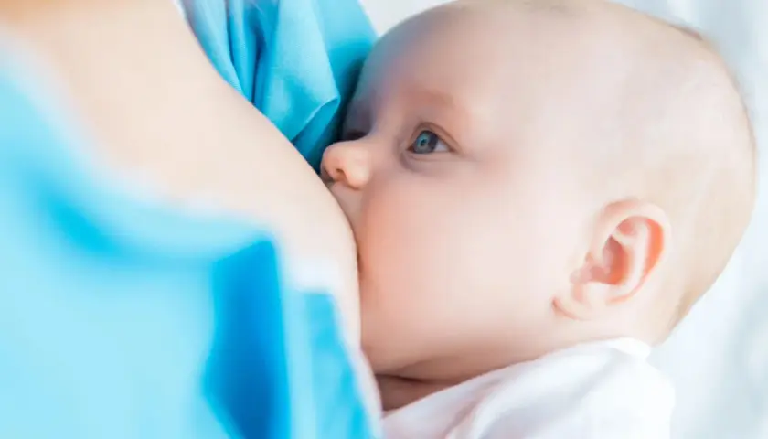 Un neonato si nutre al seno. La domanda su quanto deve mangiare un neonato è comune tra i neogenitori.