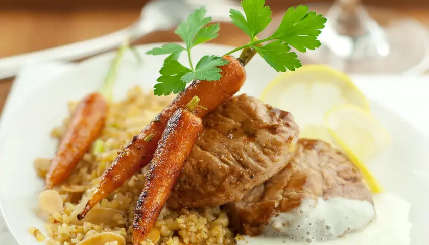Délicieux grenadin de veau, servi avec des carottes glacées, du boulgour et une sauce crémeuse.