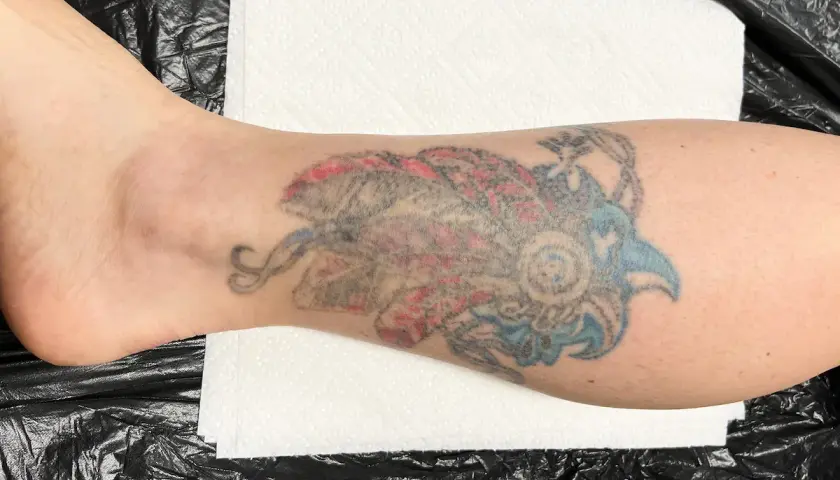 Kolorowy tatuaż w stylu irezumi polska na łydce, przedstawiający stylizowanego ptaka lub smoka.
