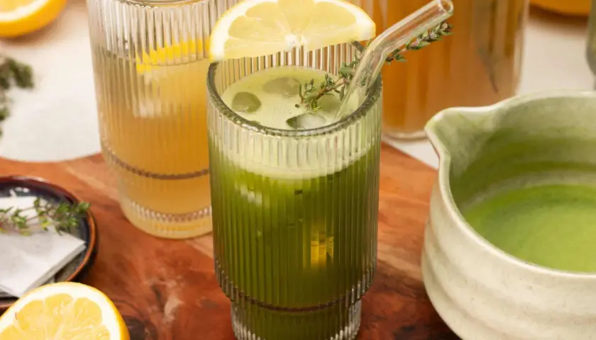 Erfrischender Eistee: Matcha kalt zubereiten mit Zitrone und Minze. Ein Glas mit Eiswürfeln, grüner Flüssigkeit und einer Zitronenscheibe.