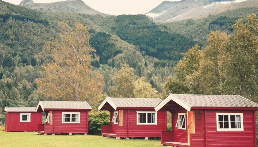 Czerwone domki kempingowe w malowniczej scenerii górskiej, idealne na camping w Norwegii.