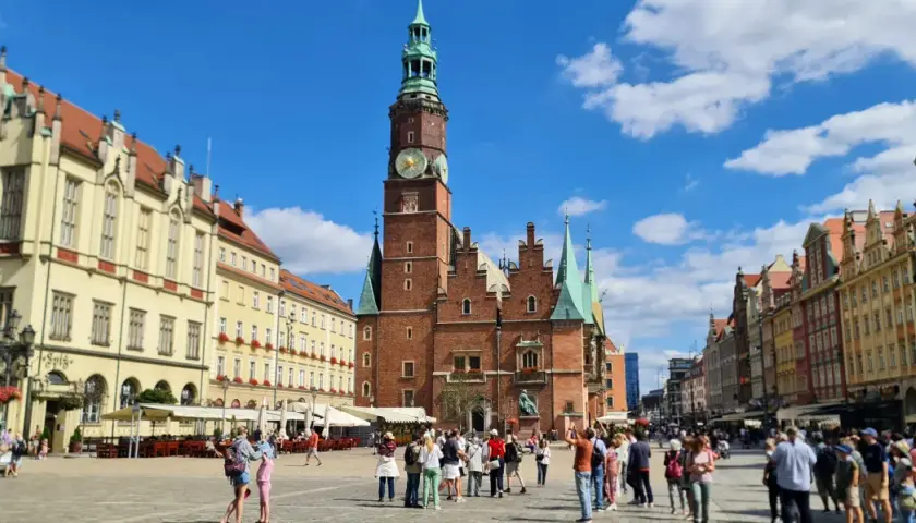 Tętniący życiem Rynek we Wrocławiu, z Ratuszem w centrum. Ludzie spacerują, podziwiając piękną starówkę wrocław.