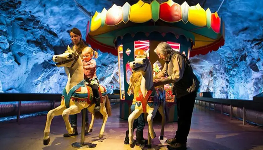Familj njuter av en karusell i en grotta, en del av Stockholm Toy Museum.