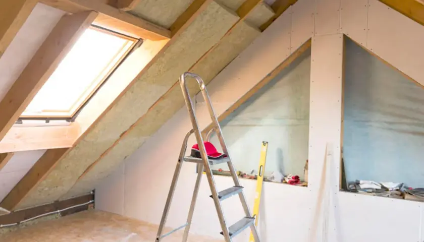 Dachboden ausbauen: Isolierung, Dachfenster und Trockenbauwände schaffen neuen Wohnraum. Werkzeug und Material sind bereit.