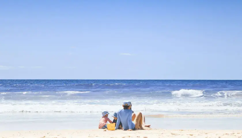 Dzieci bawią się na plaży z widokiem na spokojne morze i błękitne niebo.