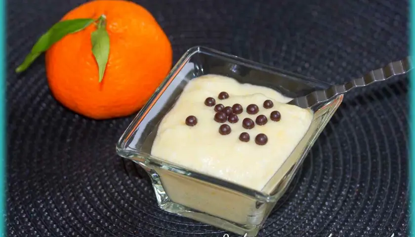 Mousse clémentine mascarpone légère et aérienne, décorée de perles de chocolat. Une clémentine fraîche à côté.