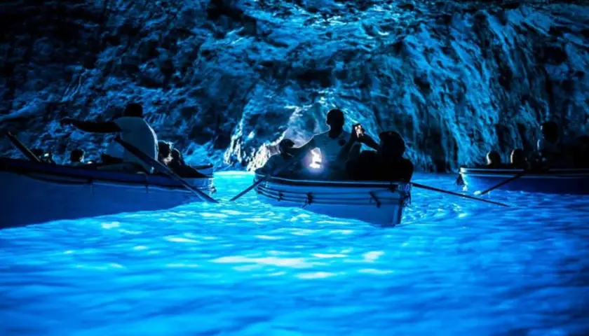 Barche a remi navigano nelle acque luminose della Grotta Azzurra, un luogo magico dove si trova questo spettacolo naturale.