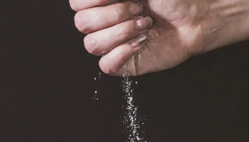 Une main saupoudre du sel, une expression culinaire qui sublime les saveurs.