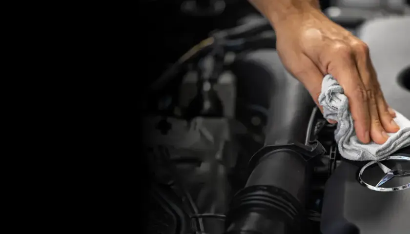 Mano limpiando el logo de Mercedes-Benz. Un detalle para el reset mantenimiento Mercedes.