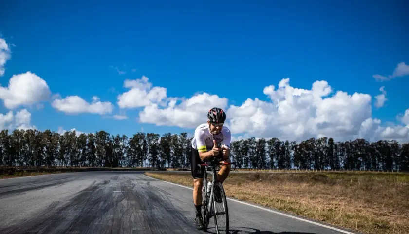 Ciclista pedaleando en la Vía de la Plata en bici, con pulgares arriba bajo un cielo azul y nubes blancas.