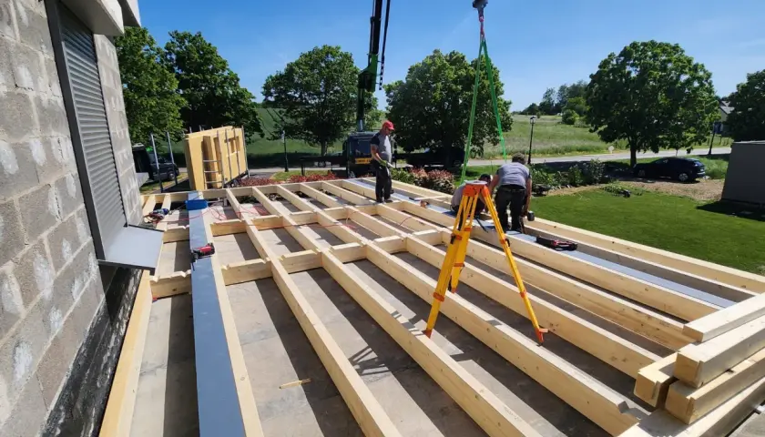 Construction d'une surélévation bois. Des ouvriers installent la structure en bois d'un étage supplémentaire, avec une grue en arrière-plan.