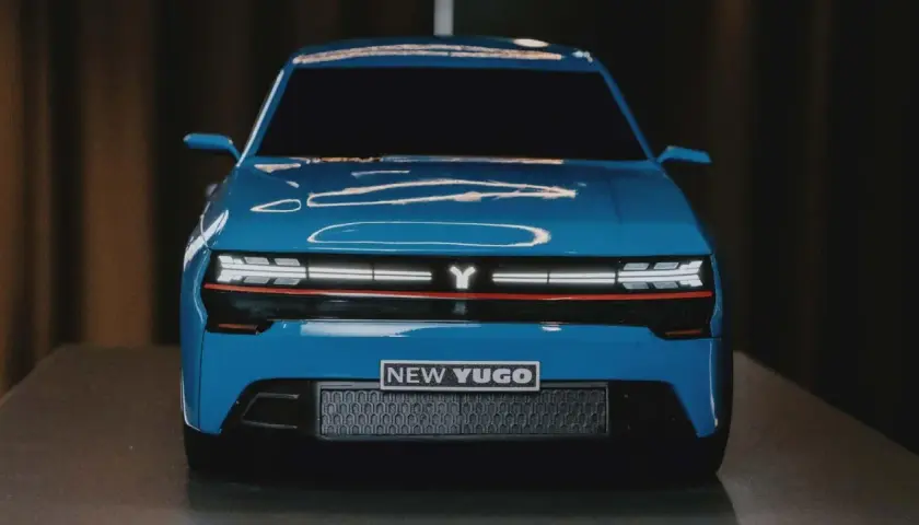 En blå, modern yugo bil med en Y-logotyp och texten "NEW YUGO" på fronten.