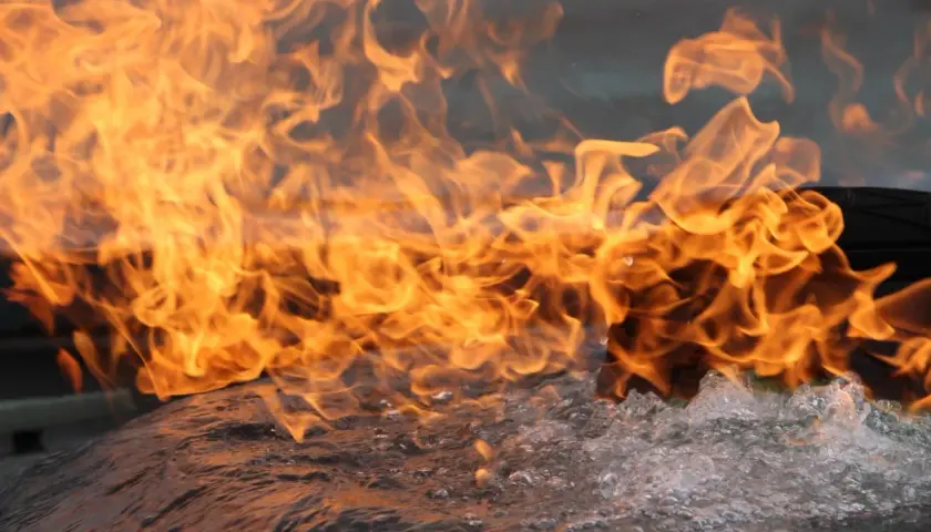Flammen lodern über sprudelndem Wasser. Das Brandverhalten von CFL-S1-Materialien wird hier eindrucksvoll demonstriert.