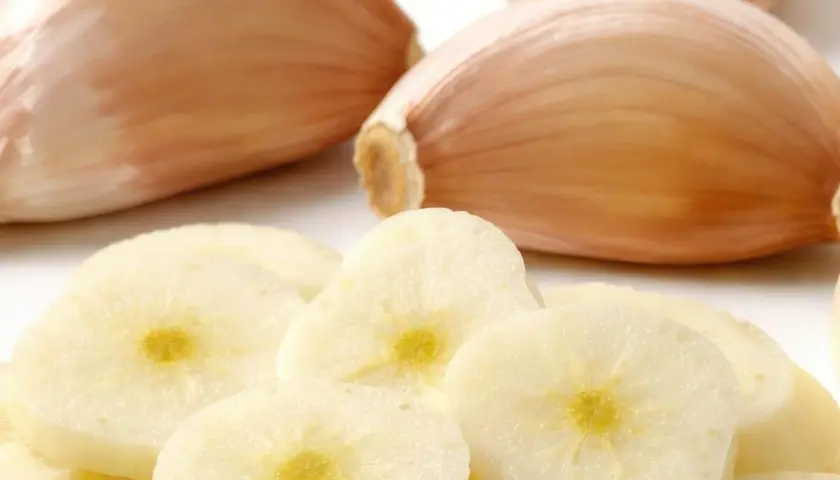 Frische Knoblauchzehen und Scheiben. Woran erkennt man schlechten Knoblauch? An weichen Zehen und verfärbten, matschigen Scheiben.