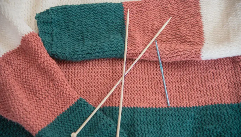 Kolorowy, dziergany sweter z drutami i szydełkiem.
