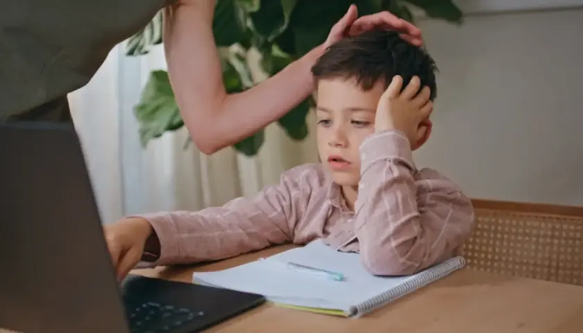 Chłopiec zapatrzony w ekran, z ręką na głowie, wygląda, jakby gdy dziecku na niczym nie zależy. Mama próbuje go zachęcić.