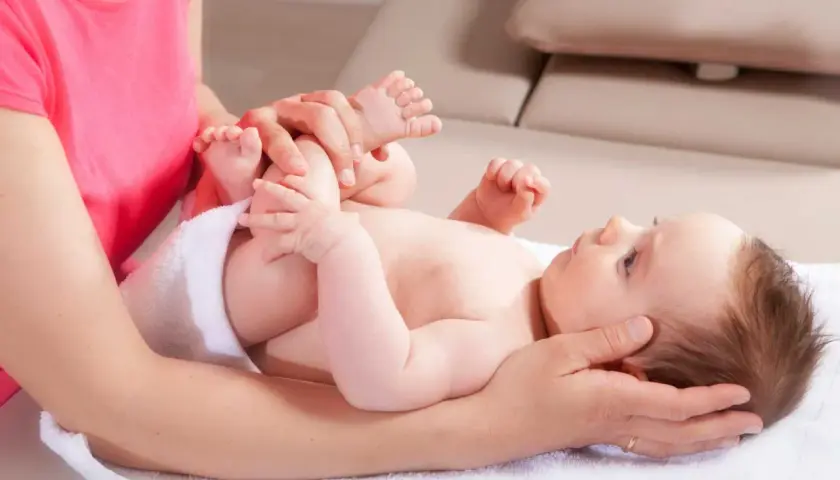 Sanfte Hände untersuchen die Füße eines Babys. Eine Mutter fragt sich, wann mit Baby zum Osteopathen gehen sollte, um solche Behandlungen zu erhalten.