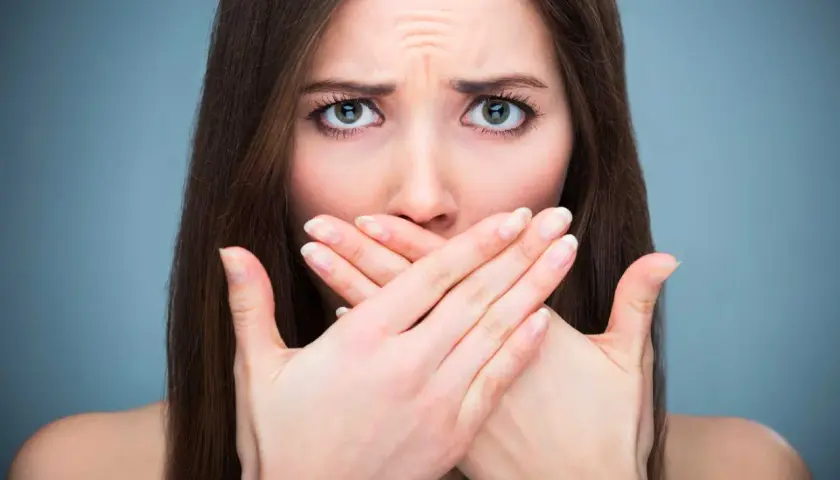 Donna con mani sulla bocca, espressione preoccupata, forse per la salivazione eccessiva.