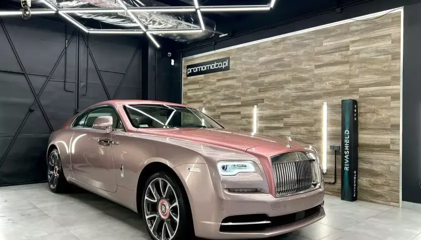 Luksusowy Rolls-Royce w różowym odcieniu, prezentujący efektowne oklejenia samochodu.