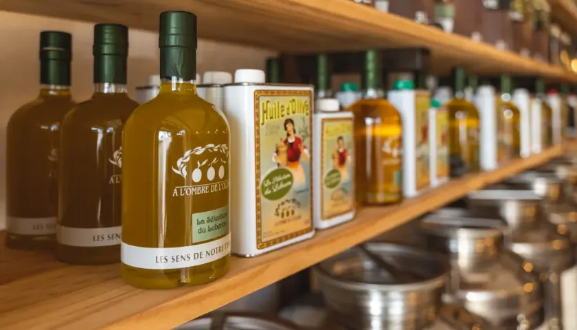 Bouteilles d'huile d'olive "Les Sens de Notre Terre", "A l'ombre de l'Oli" et "La Sélection du Luberon", évoquant les saveurs des terrasses d'Adrien.